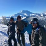A group of people standing on top of a snow covered slope.